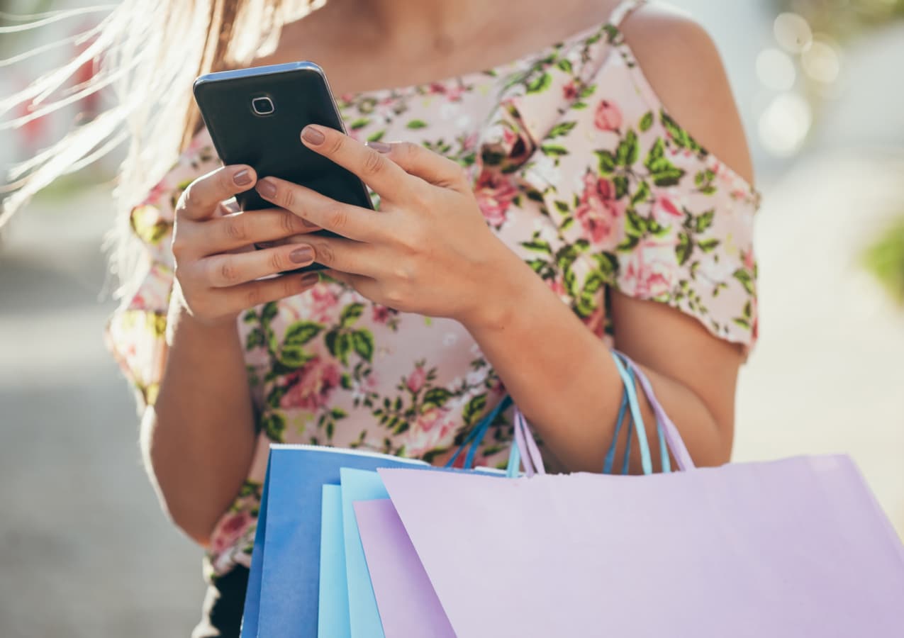 a woman holding a phone while shoppinh showing a mobile app for e-commerce